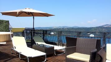A terrace with wicker furniture, a table, and an umbrella.