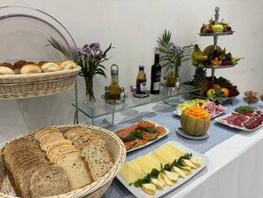 Une table de buffet proposant divers aliments, notamment du pain, du fromage et des fruits.