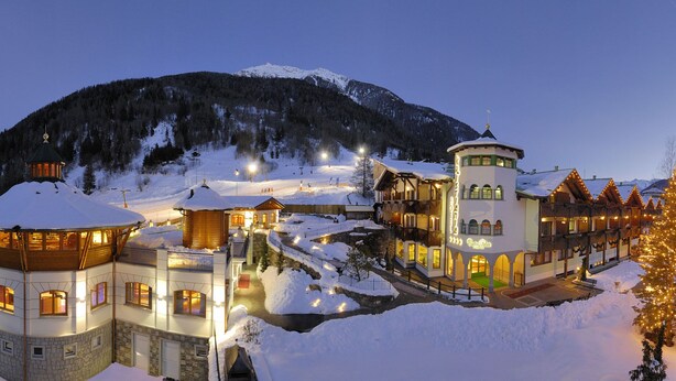 A snow-covered mountain resort with illuminated buildings and a snow-covered road. - Kristiania Pure Nature Hotel & Spa (Pejo)