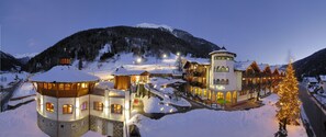 A snow-covered mountain resort with illuminated buildings and a snow-covered road. - Kristiania Pure Nature Hotel & Spa (Pejo)