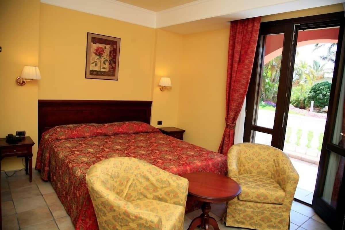 Une chambre d’hôtel avec un grand lit, deux tables de chevet, une chaise et une vue sur l’extérieur.