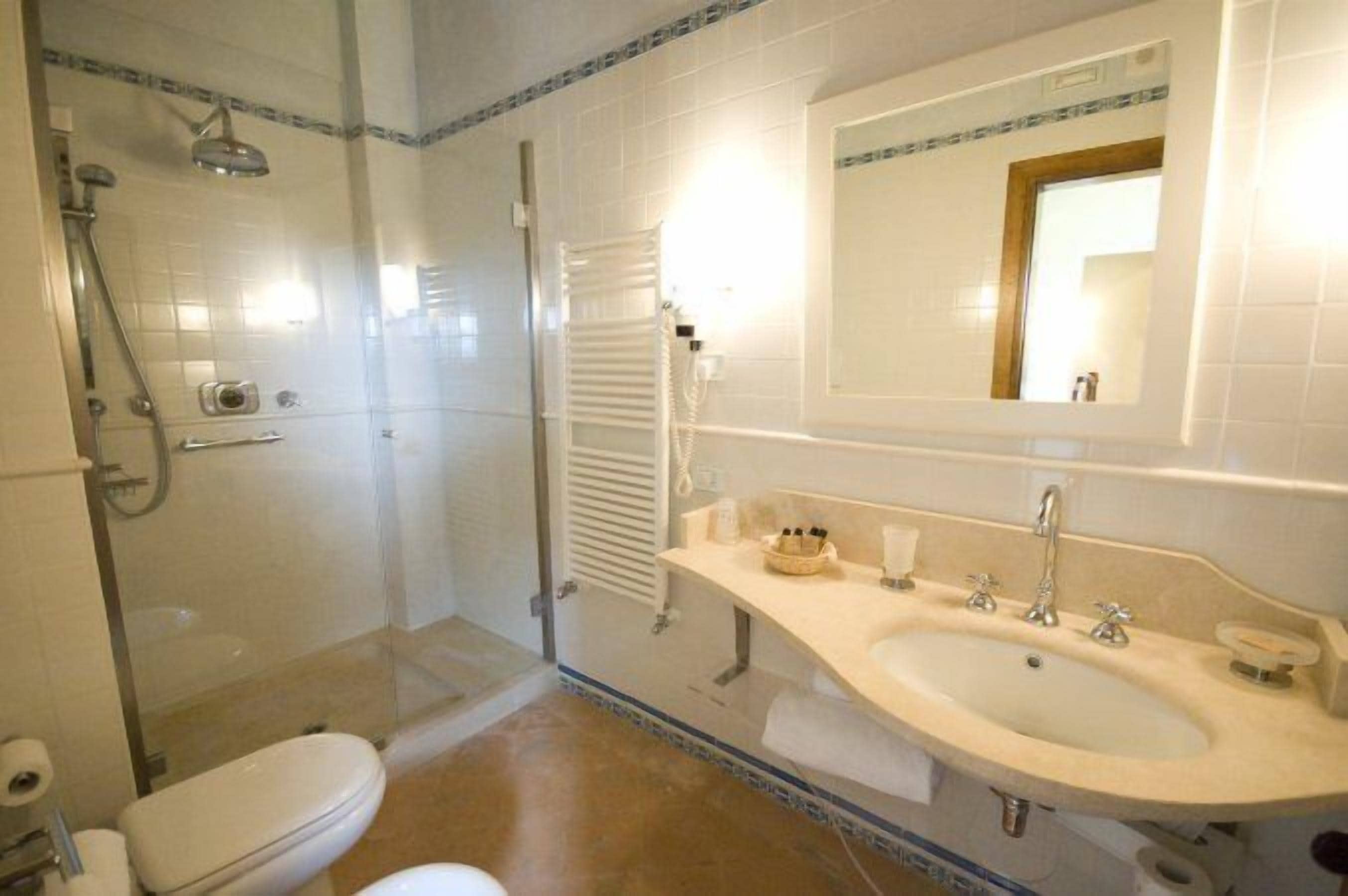 A bathroom with a glass-enclosed shower, a sink with a mirror above it, and a toilet.