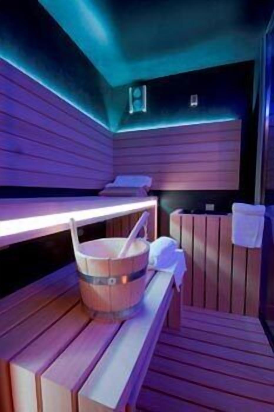 Un cuarto de sauna con bancos de madera, un balde y un perchero para toallas.