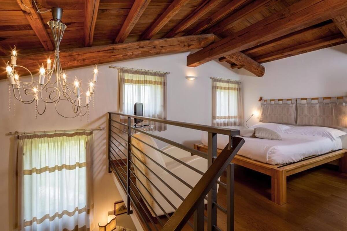 A bedroom with a wooden bed, a chandelier, and a staircase.