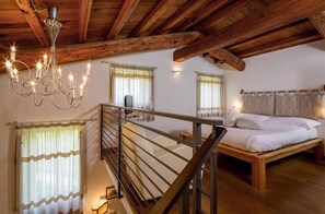 A bedroom with a wooden bed, a chandelier, and a staircase.