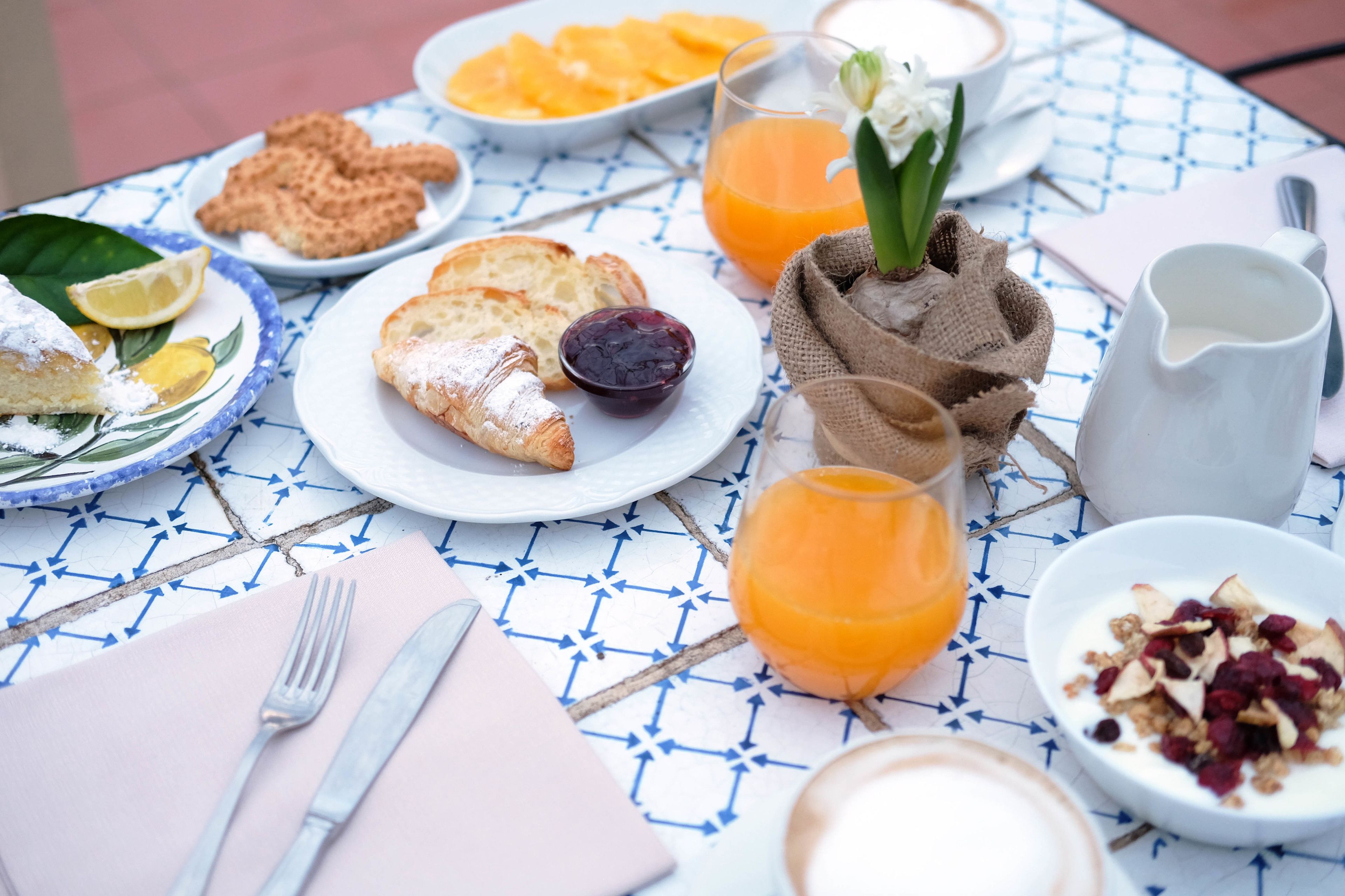 A breakfast table with plates of food, a pitcher, and a glass of orange juice.