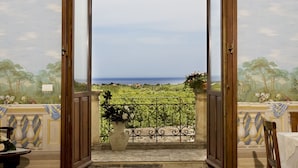 Une porte ouverte donnant sur un balcon avec vue sur la mer.