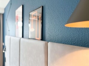 A wall with a textured blue surface and a large, light-colored padded bench. - ibis Martigues (Martigues)