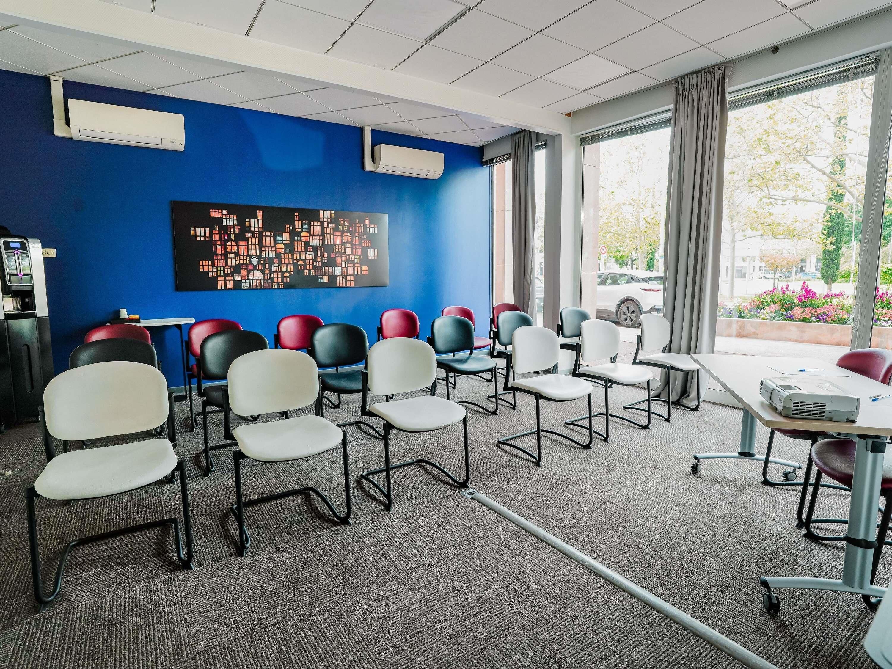 A conference room with a blue wall, a black artwork, and a view of the outdoors.