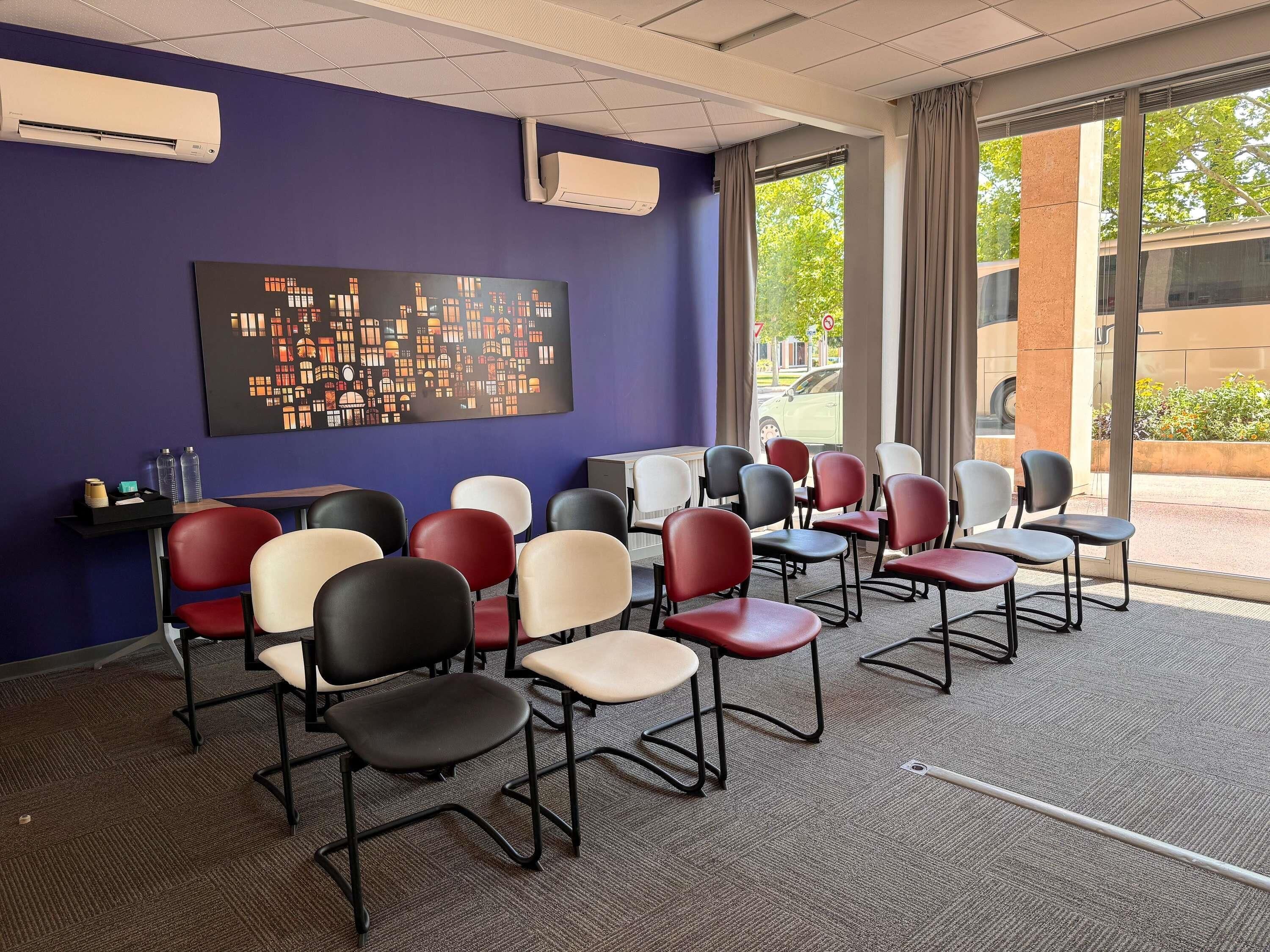 A conference room with multiple chairs, a large abstract painting on the wall, and air conditioning units.