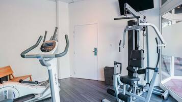 Un gimnasio con una máquina elíptica, una máquina de pesas y una banca.