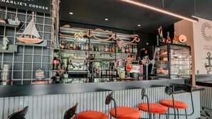 A bar area with a counter, stools, and various bottles and glasses. - ibis Martigues (Martigues)