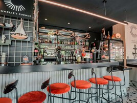 Zona de bar con mostrador, taburetes y diferentes botellas y vasos.