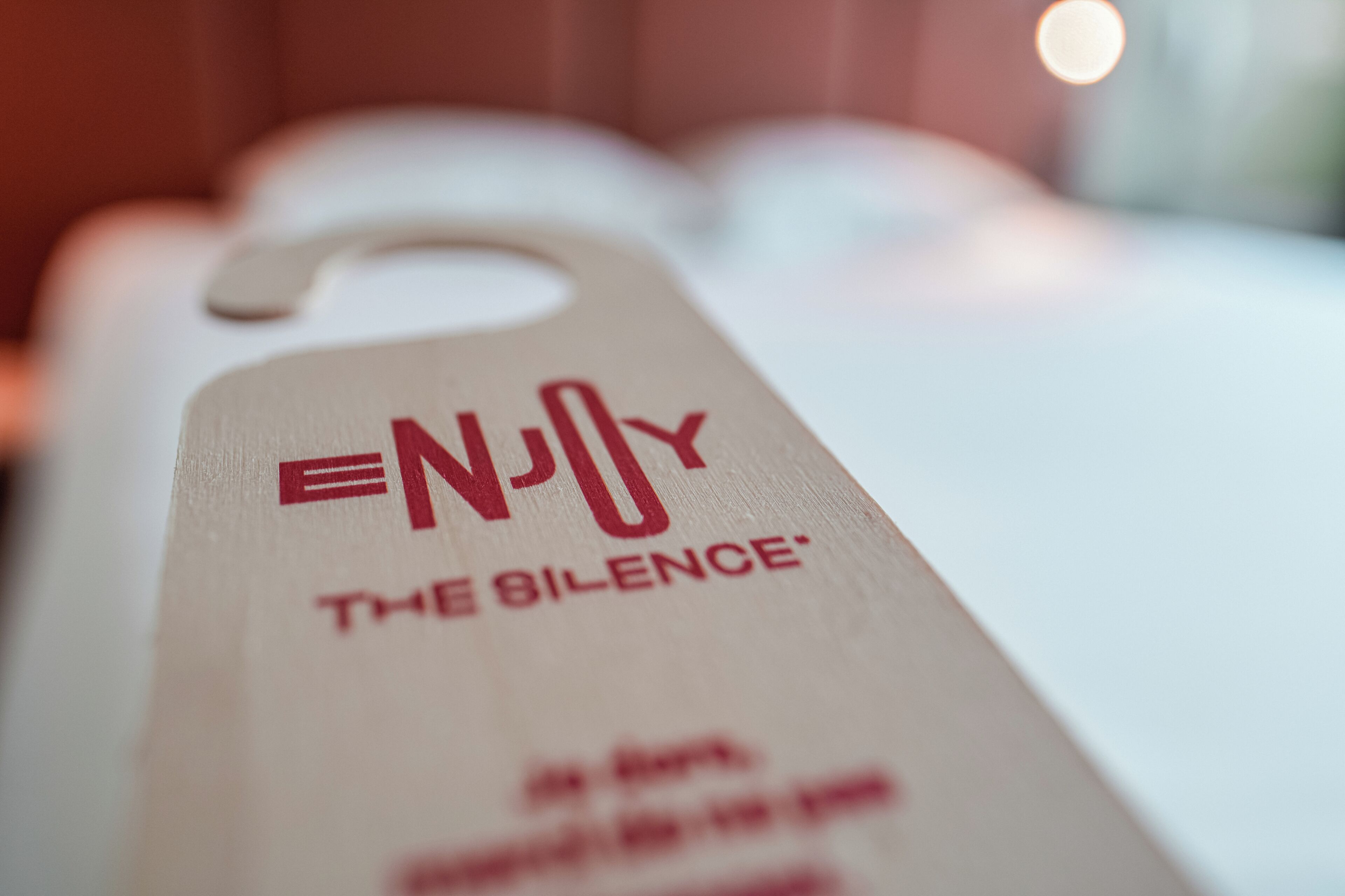 Une étiquette portant le texte « PROFITEZ DU SILENCE » et une vue partielle d’une pièce avec une table blanche.
