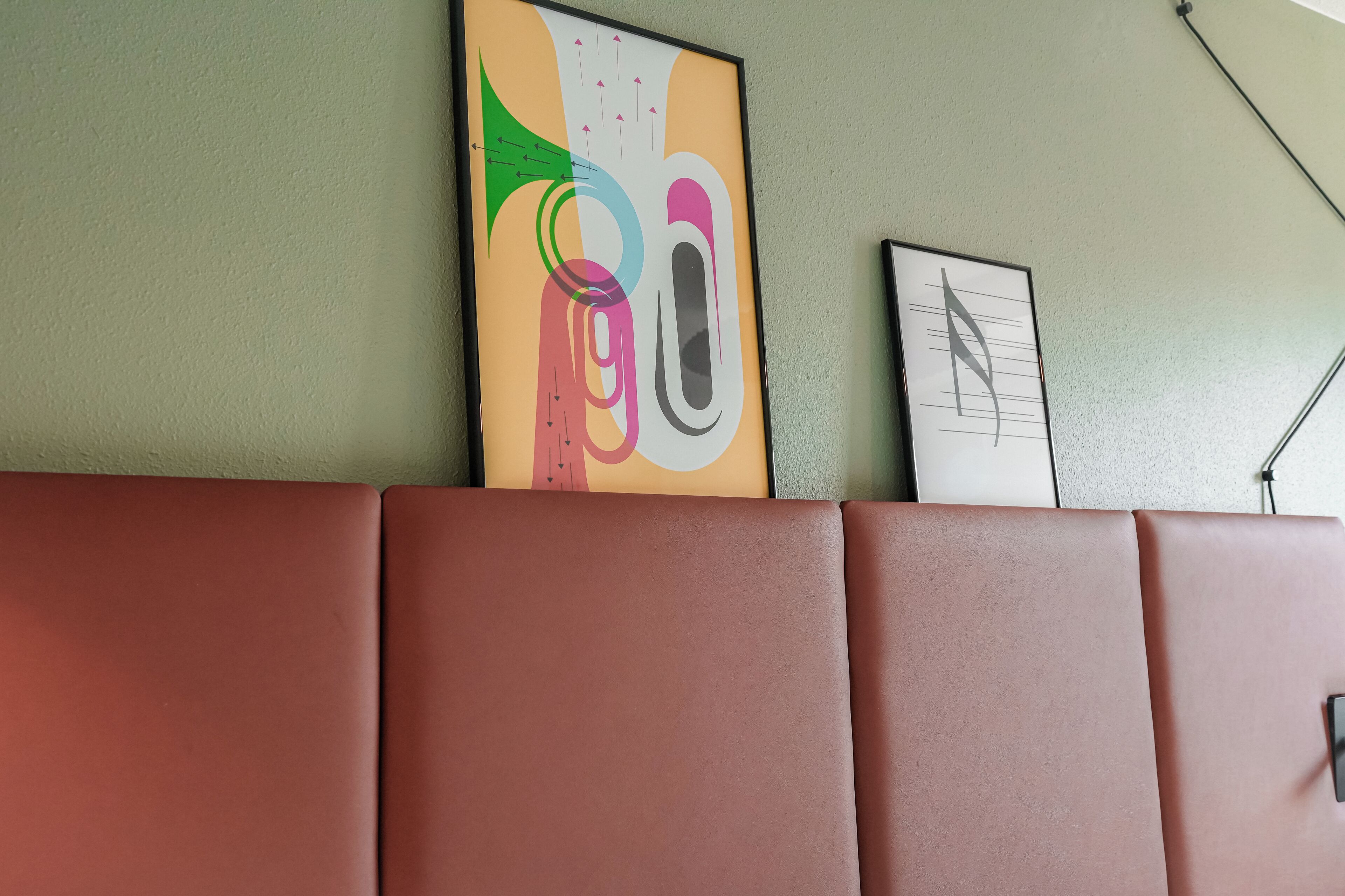 Un mur orné de deux œuvres d’art encadrées, un canapé et une lampe.