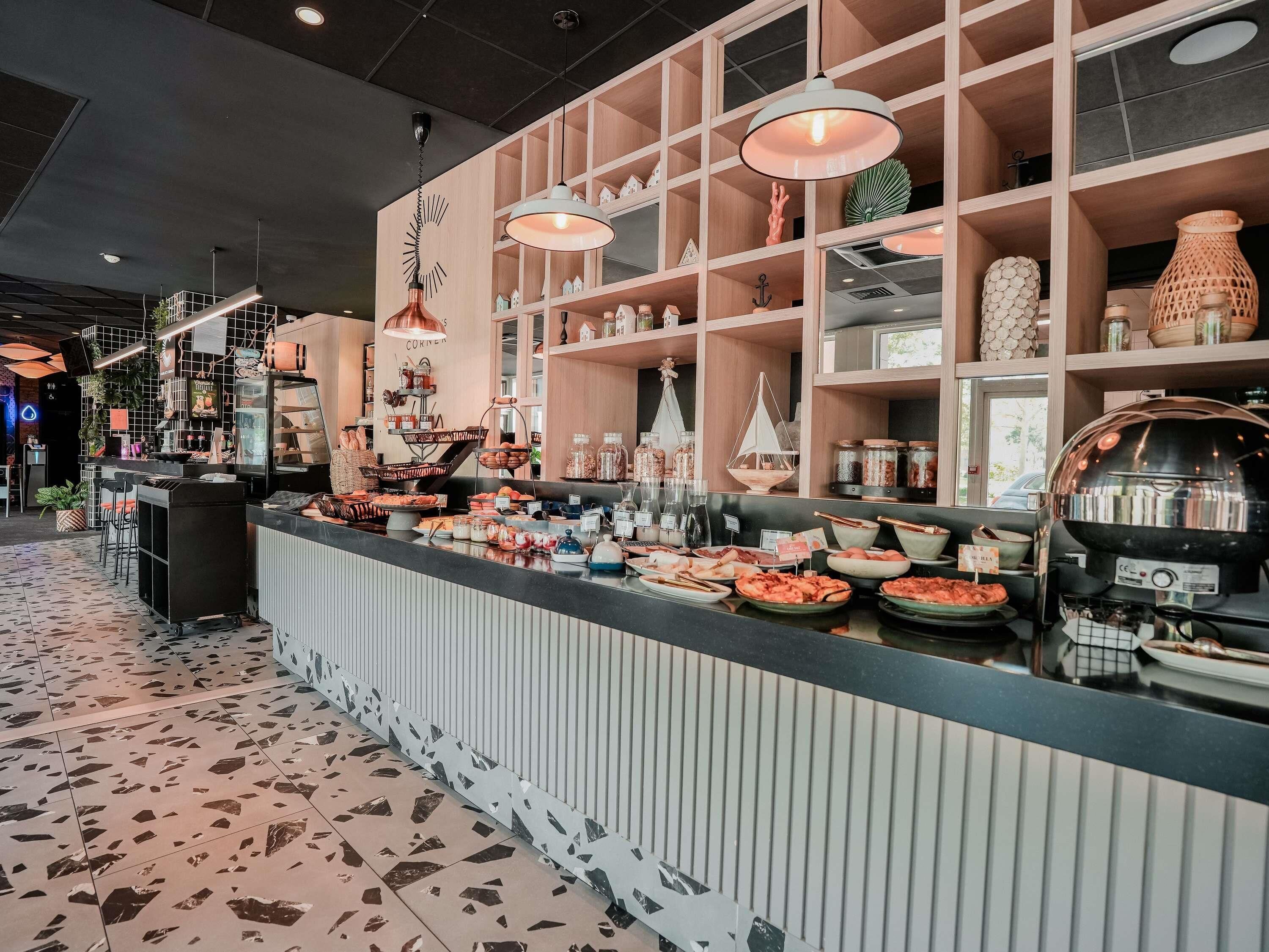 Un área de bufé con diferentes opciones de comida, una barra con caja registradora y estantes con objetos decorativos.