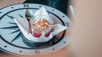 Un postre en un recipiente transparente sobre una mesa con diseño de brújula.