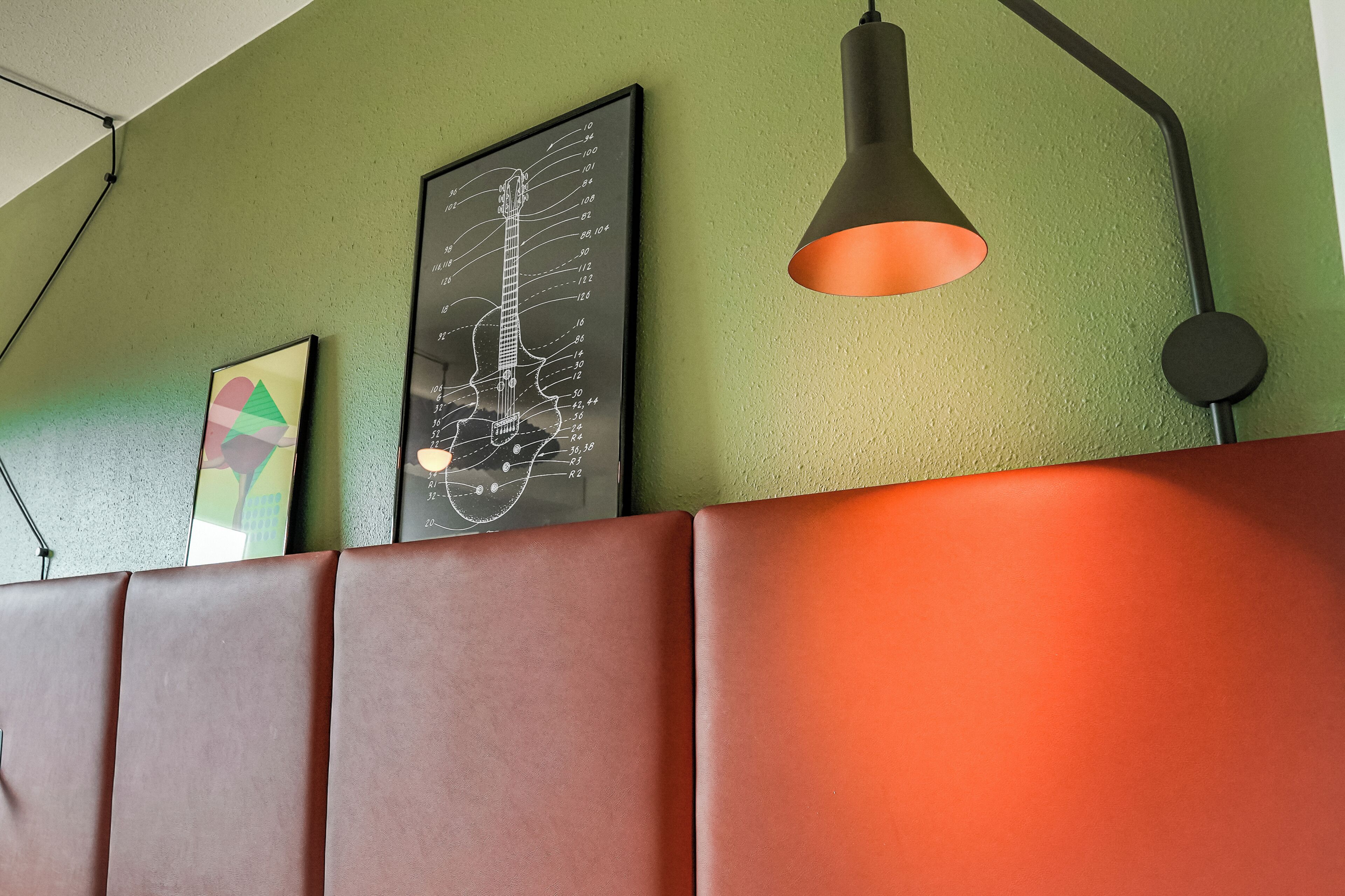 Una pared con un diagrama de diapasón de guitarra, una lámpara colgante y una obra de arte geométrica.