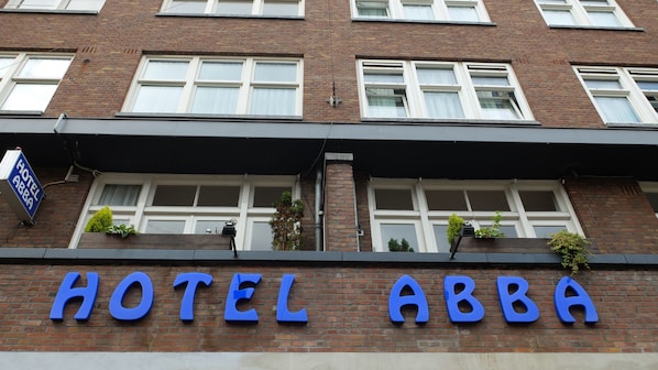 Fachada de hotel con el nombre "HOTEL ABBA" en letras azules grandes.