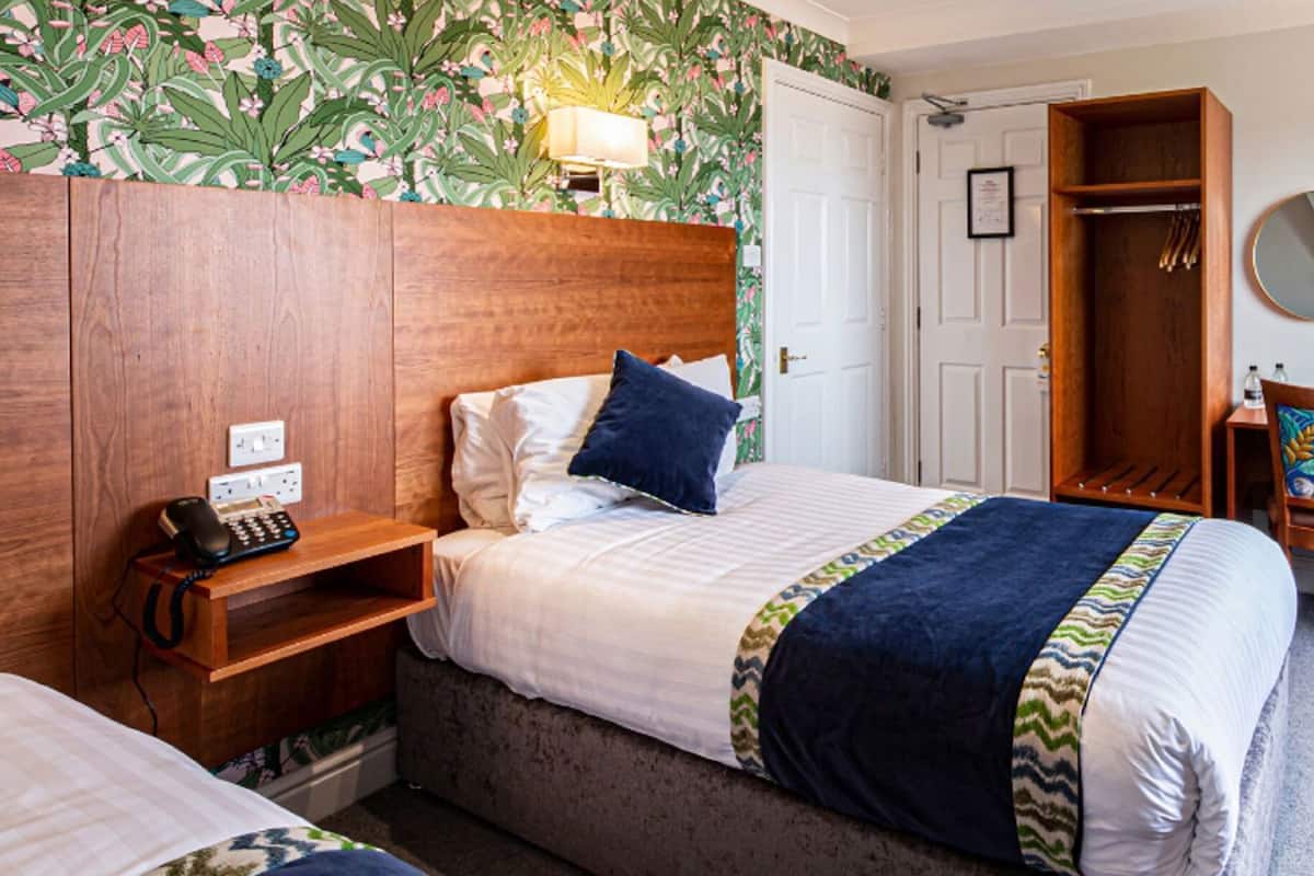 A hotel room with a bed, bedside table, chair, wardrobe, and a window.