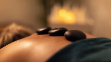 Gros plan d’une pierre de massage posée sur le dos d’une personne.