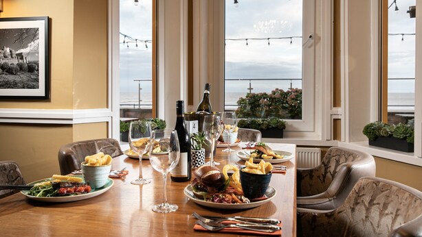 Une table à manger dressée avec des assiettes remplies de nourriture, des verres à vin et une bouteille de vin.