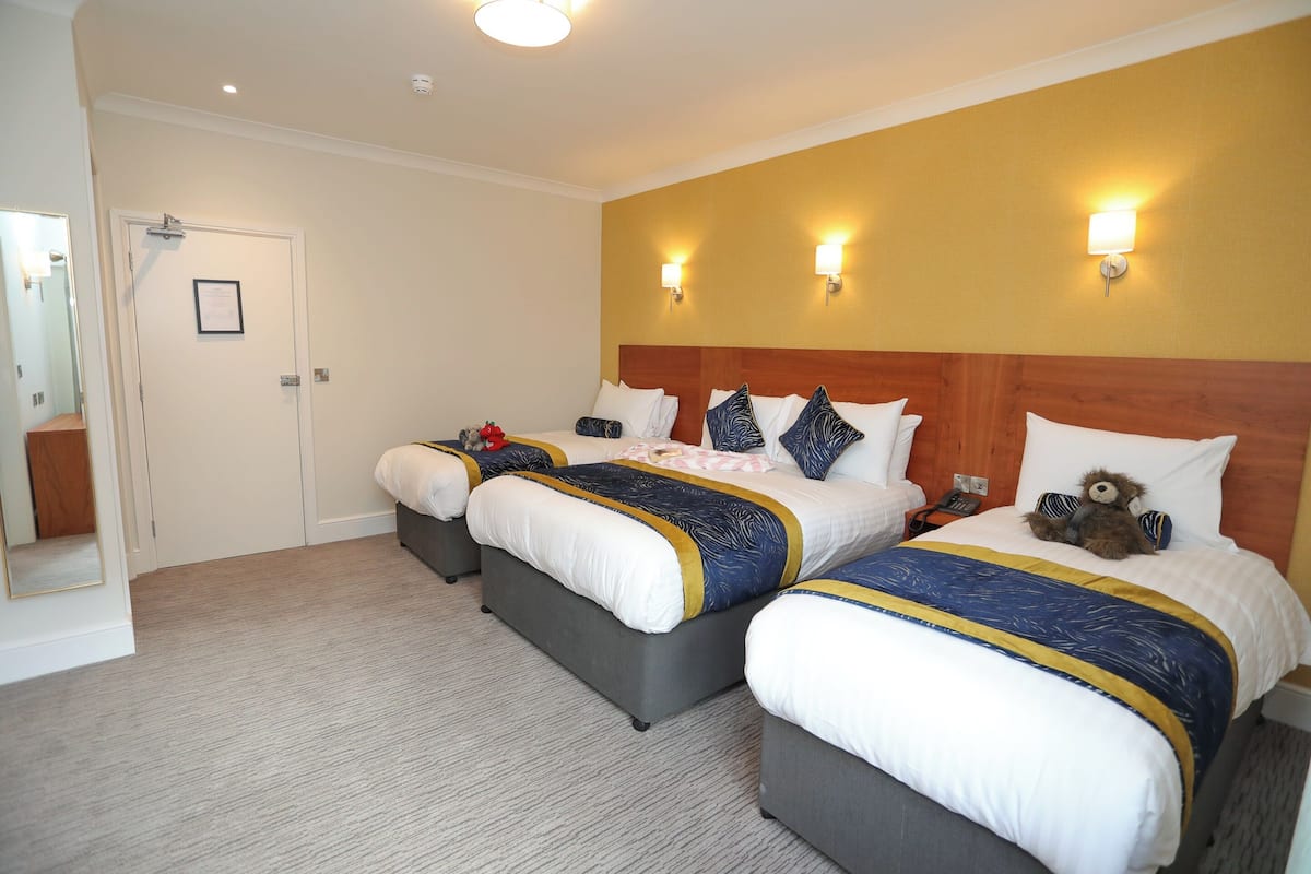 A hotel room with two beds, a wooden headboard, and a mirror.