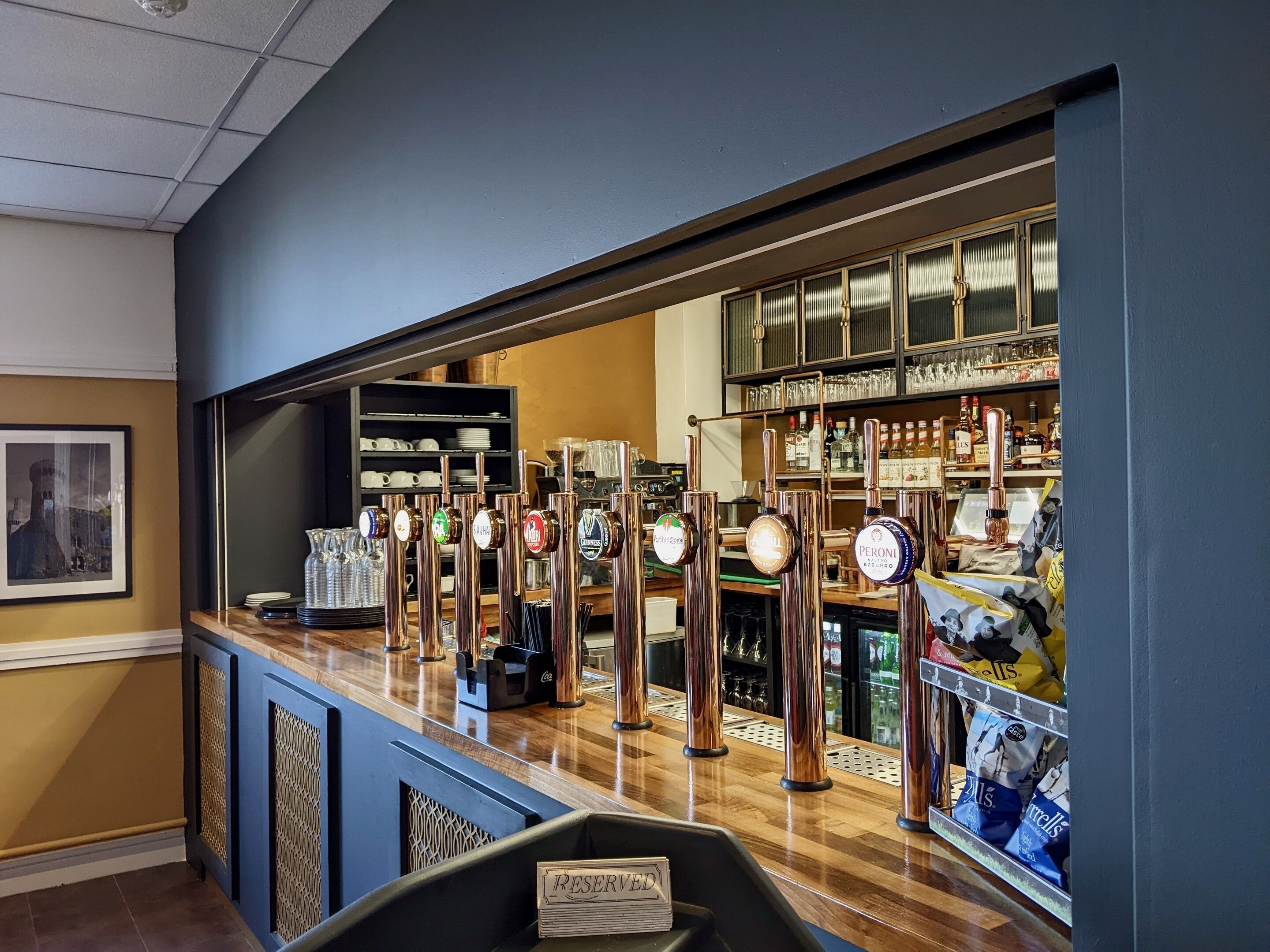 Eine Bar mit mehreren Zapfhähnen, Regalen voller Flaschen und einem Schild mit der Aufschrift 'RESERVATION'.