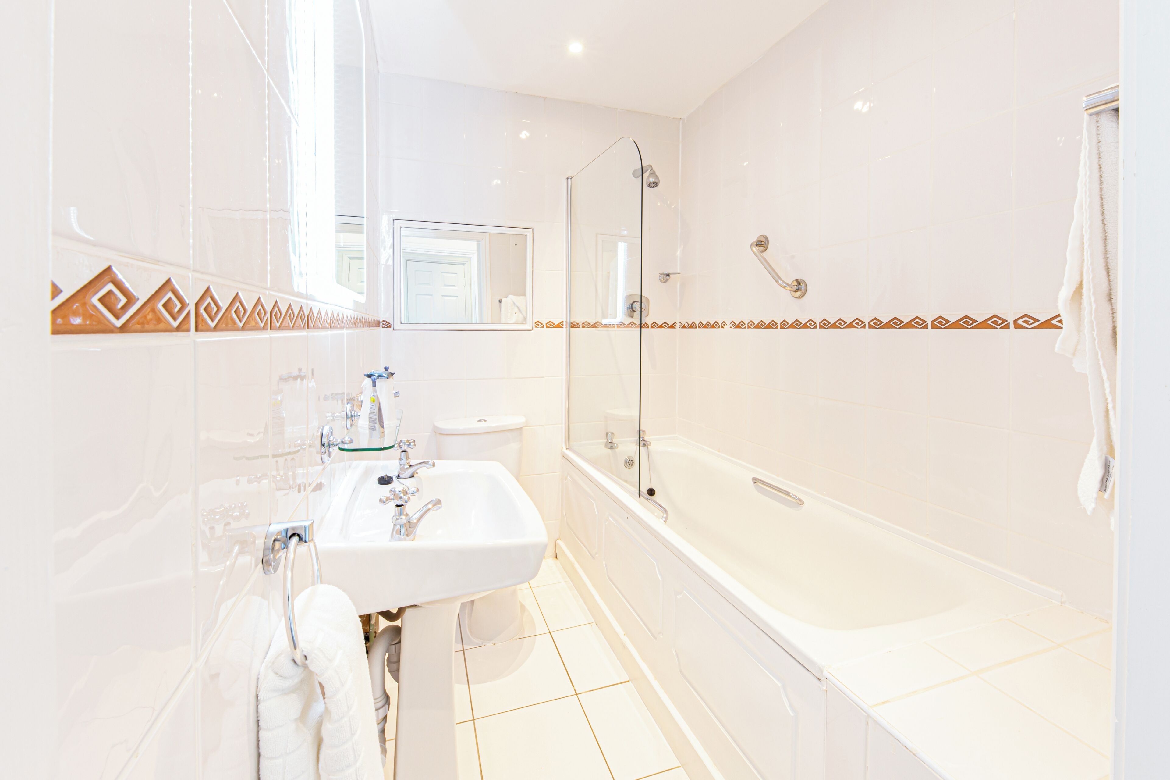 A modern bathroom with a glass-enclosed shower, a white sink, and a large bathtub.