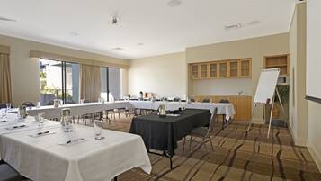 A conference room with multiple tables, white tablecloths, and chairs. There is a whiteboard on the right side.