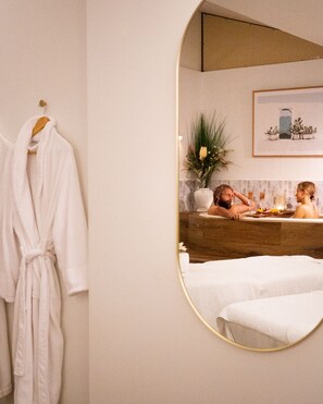 Een badkamer met een grote spiegel, een badkuip en een badjas hangend aan de muur.