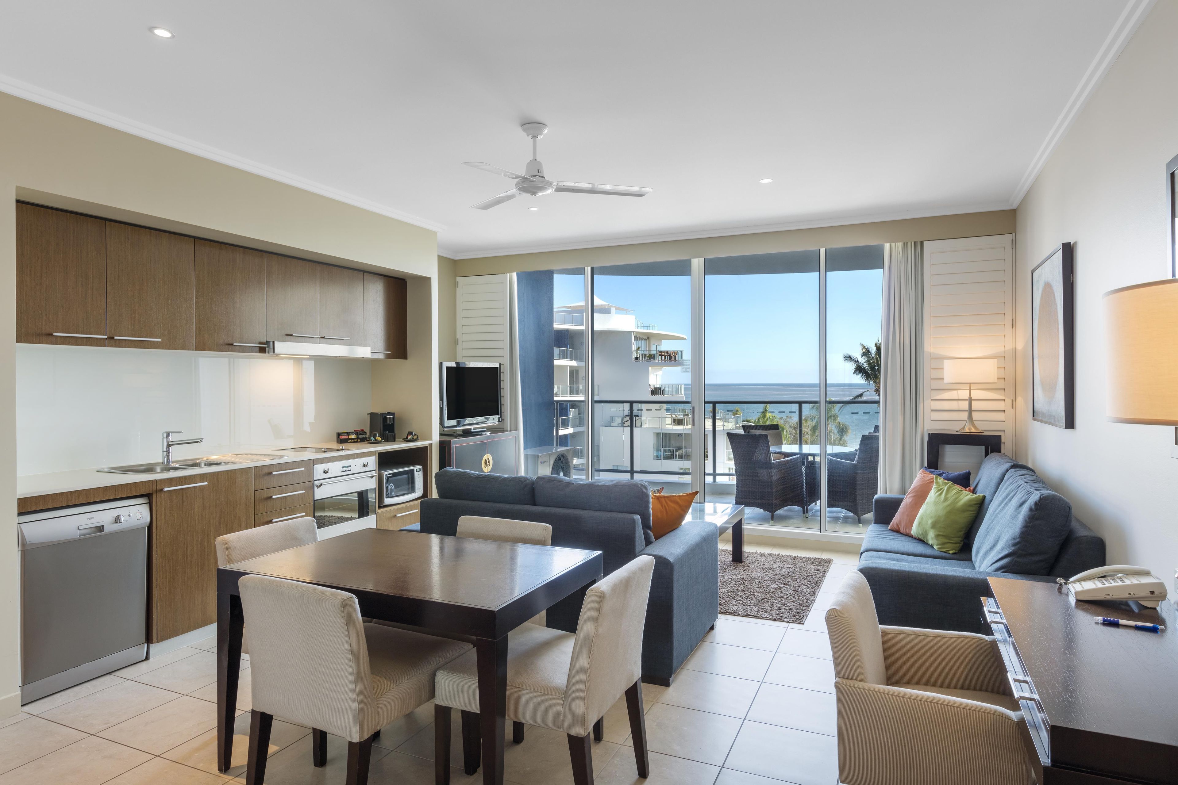 Un salon moderne comprenant un coin repas, une cuisine et un balcon avec vue sur la mer.