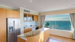 Una cocina moderna con una isla grande, electrodomésticos de acero inoxidable y vistas al mar.