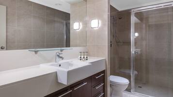 Une salle de bain moderne avec une douche à parois de verre, un lavabo blanc et un grand miroir.
