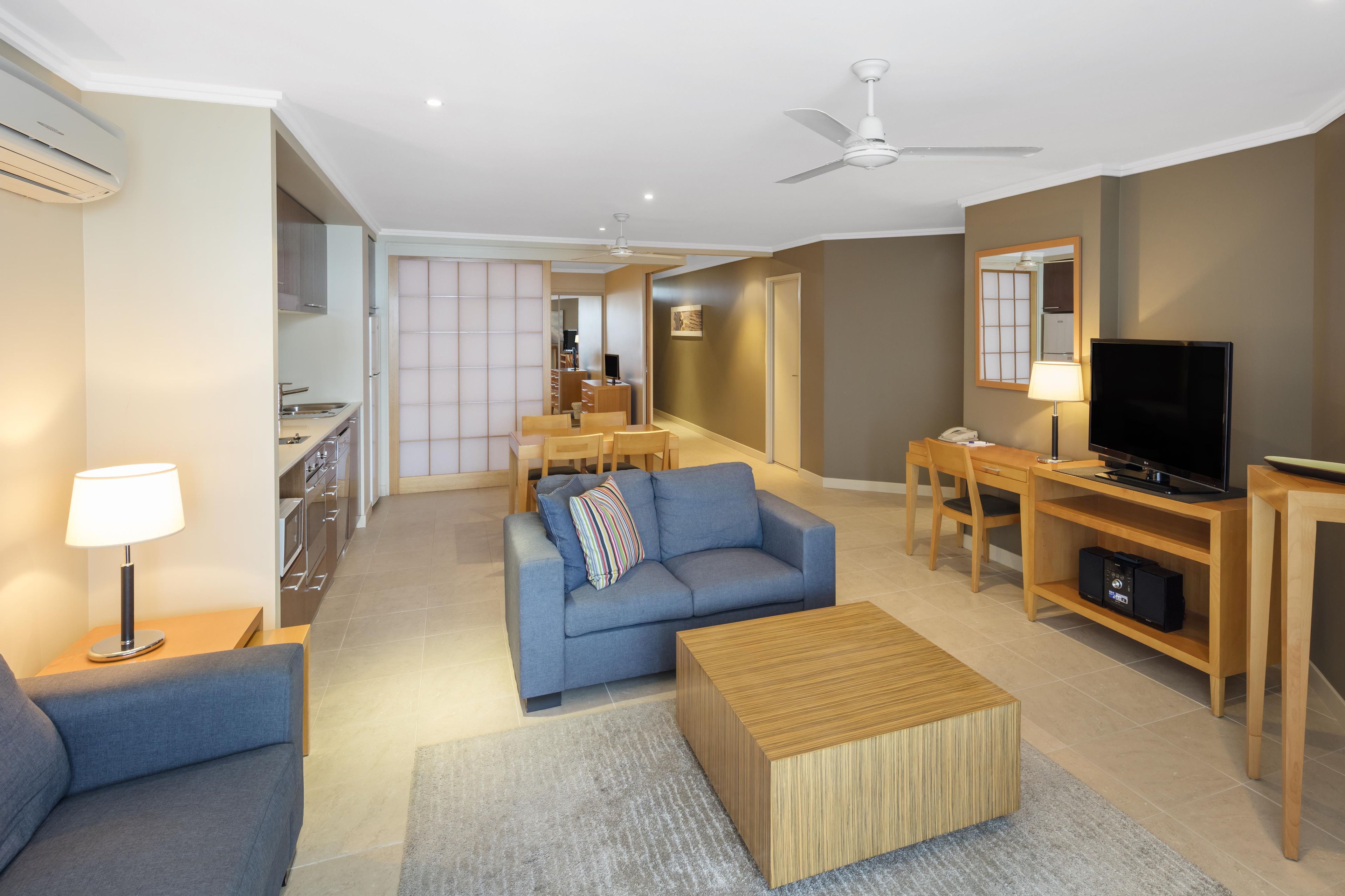 A modern living room with a sofa, a coffee table, a TV, and a dining area with chairs and a table.