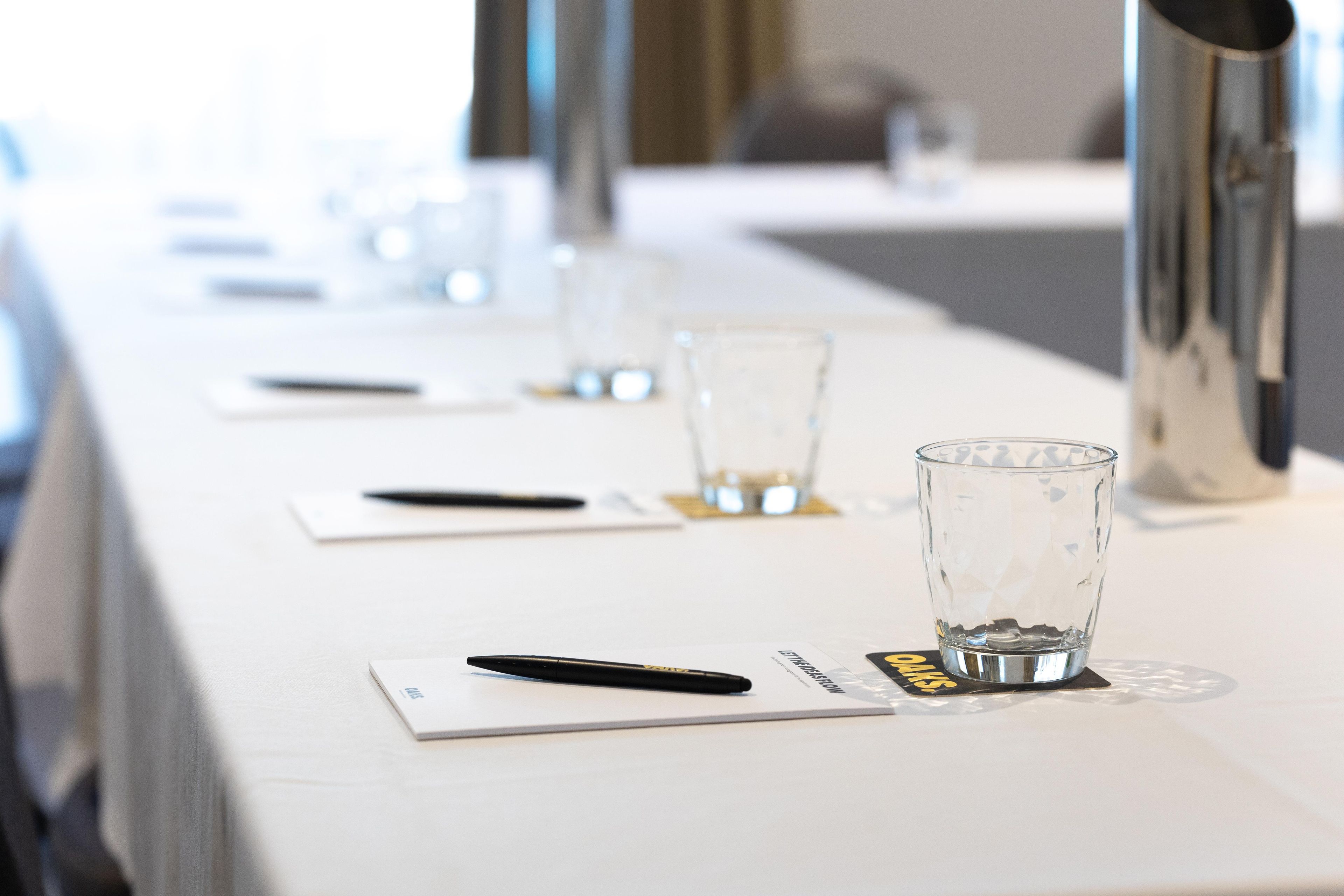 Una mesa de conferencias con vasos, bolígrafos y tarjetas de identificación.