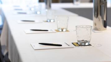 Una mesa de conferencias con vasos, bolígrafos y tarjetas de identificación.
