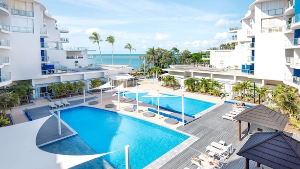 Un resort con un amplio área de piscina, varios niveles de balcones y vistas al océano.