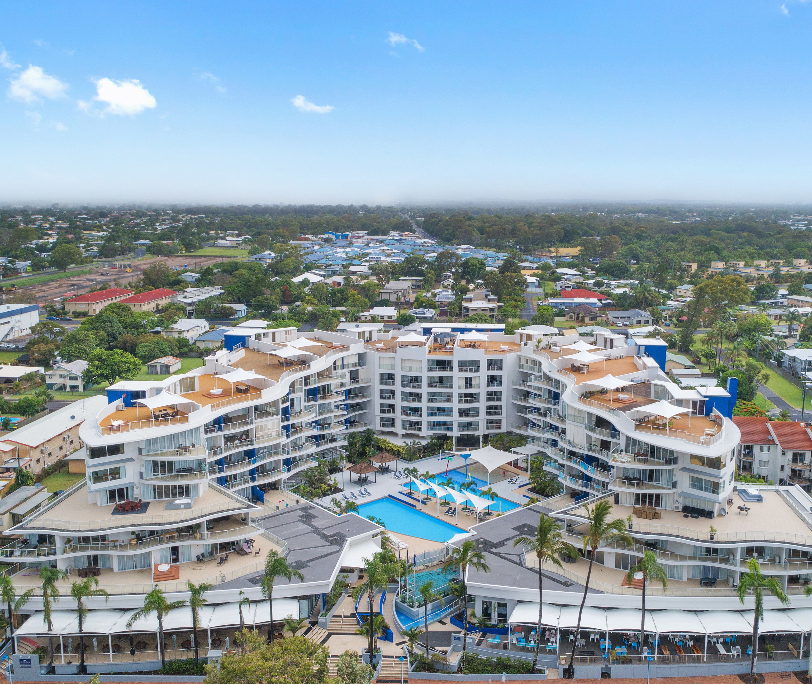 A multi-story hotel with a central swimming pool, balconies, and a view of the surrounding area.