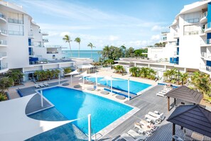 A resort with a large pool, sun loungers, and a view of the ocean.