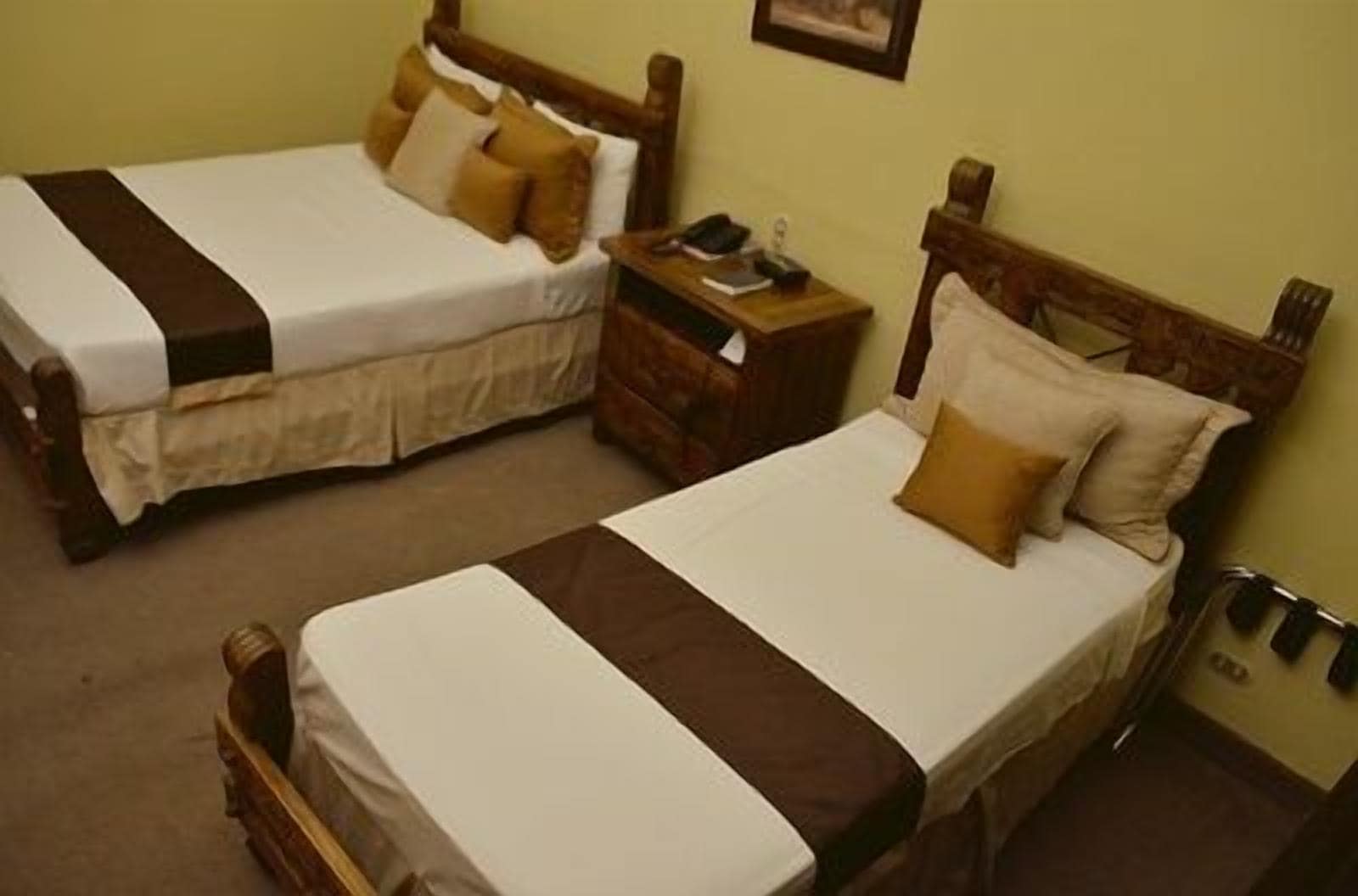 Two single beds with wooden headboards, a nightstand with a lamp, and a wall-mounted telephone.