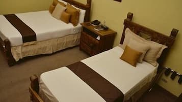 Two single beds with wooden headboards, a nightstand with a lamp, and a wall-mounted telephone.