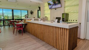 Un área de recepción moderna con un mostrador de madera, un televisor montado y un ventanal con vistas al exterior.