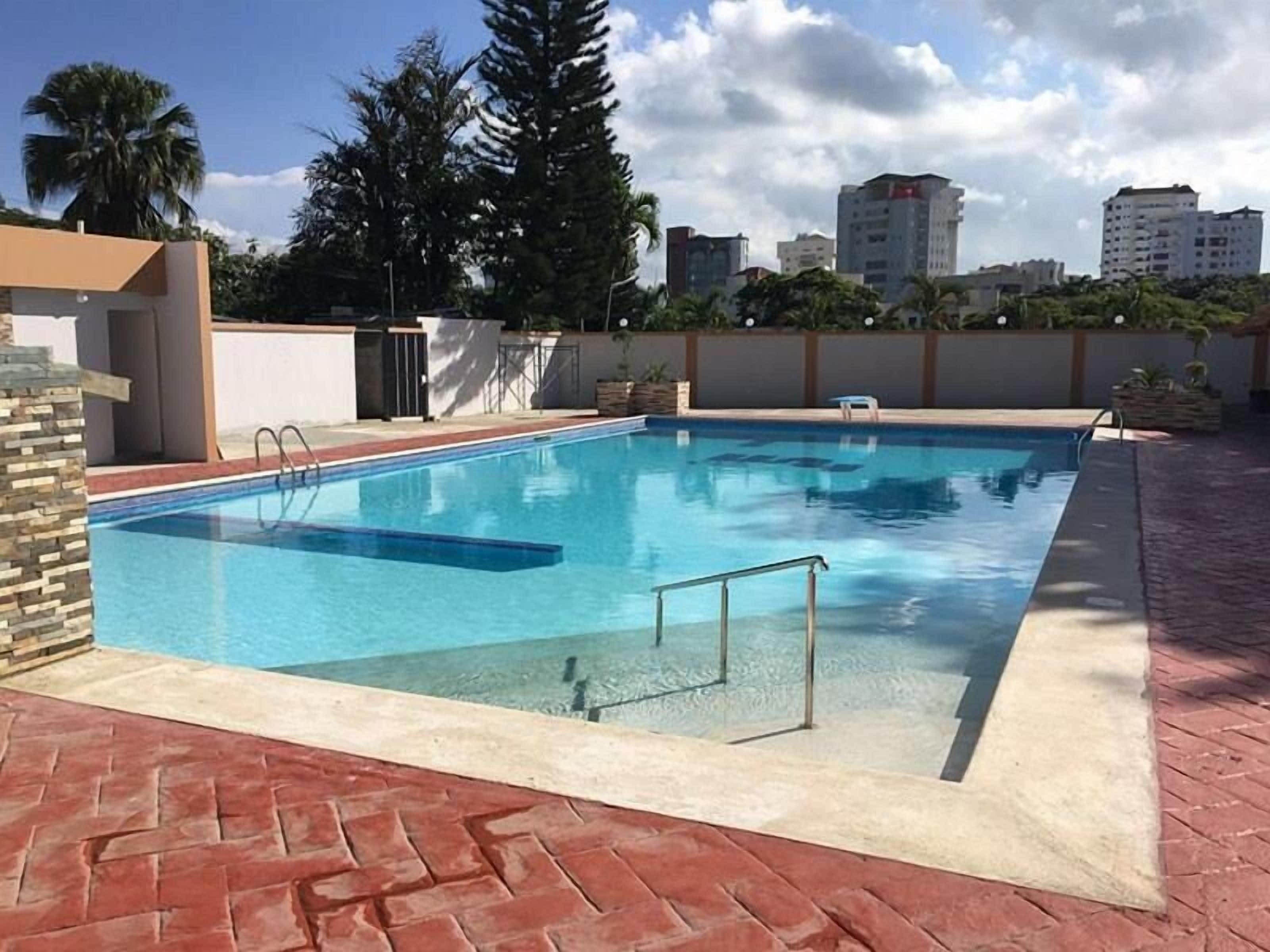 Ein rechteckiger Pool mit einer Metallleiter, umgeben von einer Pflasterterrasse.