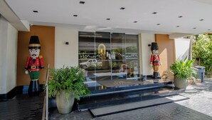 Entrada de hotel con puerta de vidrio, dos grandes figuras de soldado de hojaldre y plantas en macetas.