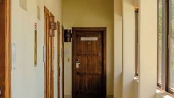 A hallway with a wooden door at the end, a ceiling light, and a window on the right.