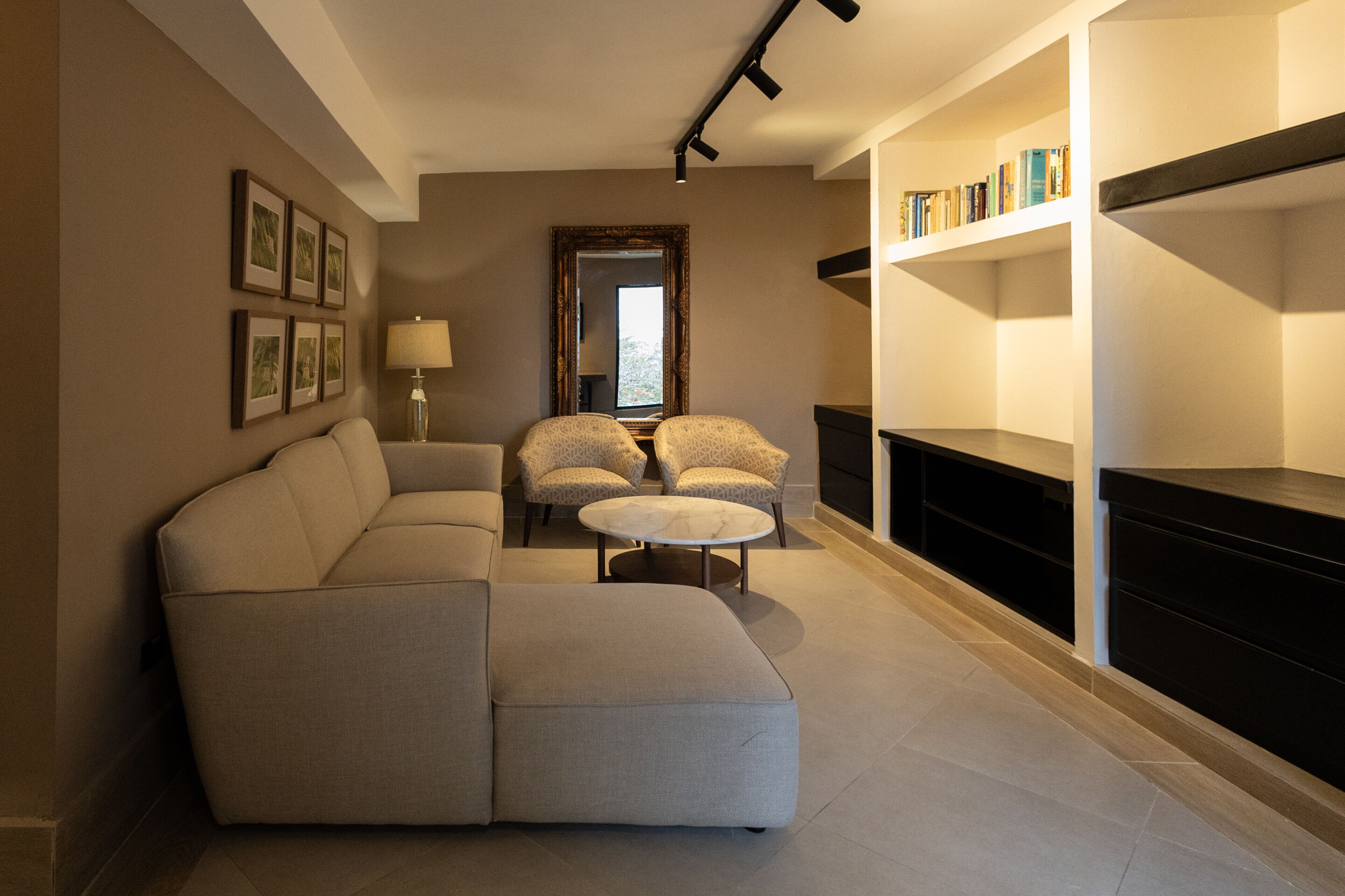 A modern living room with a sectional sofa, two armchairs, a round coffee table, a floor lamp, a fireplace, and a bookshelf.
