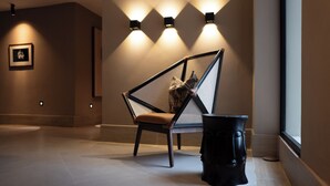A modern interior with a geometric chair, wall-mounted lights, and a framed picture. - Camp David Ranch (Santiago de los Caballeros)
