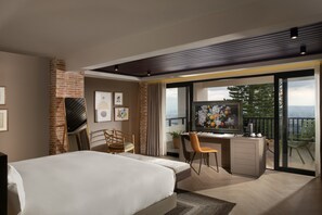 A modern hotel room with a large bed, a desk with a chair, a television, and a balcony with a view of the city. - Camp David Ranch (Santiago de los Caballeros)