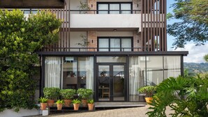 A modern two-story building with a balcony, large windows, and potted plants. - Camp David Ranch (Santiago de los Caballeros)